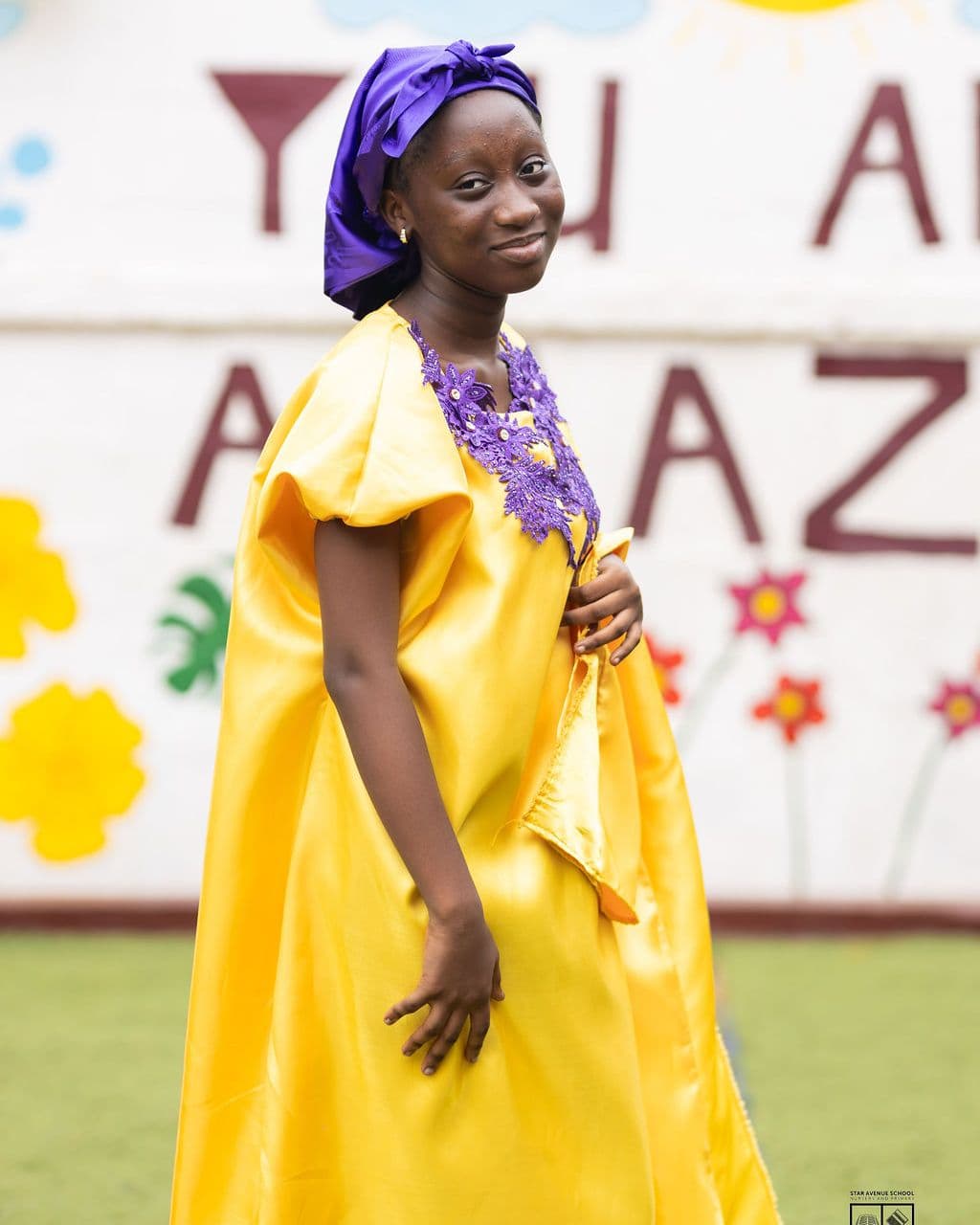 A pupil in yellow with her headwrap