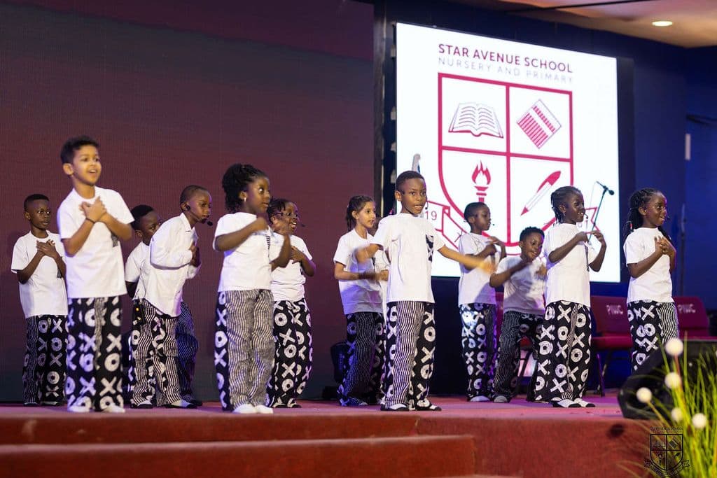 The class on stage in front of the school crest