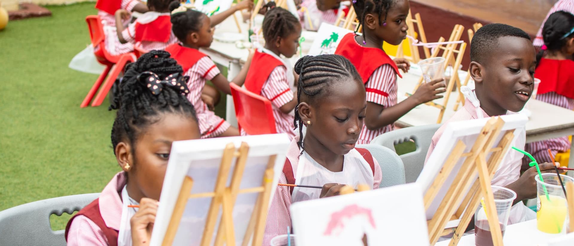 Preschool children painting side by side at easels in the courtyard