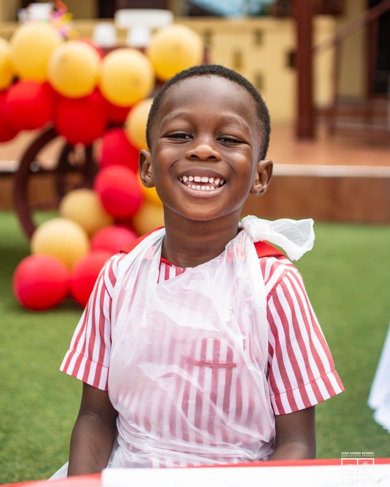A young child in a striped apron smiling broadly