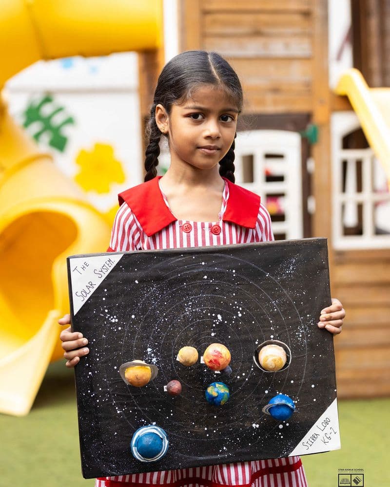 A pupil holding a painted model of the planets