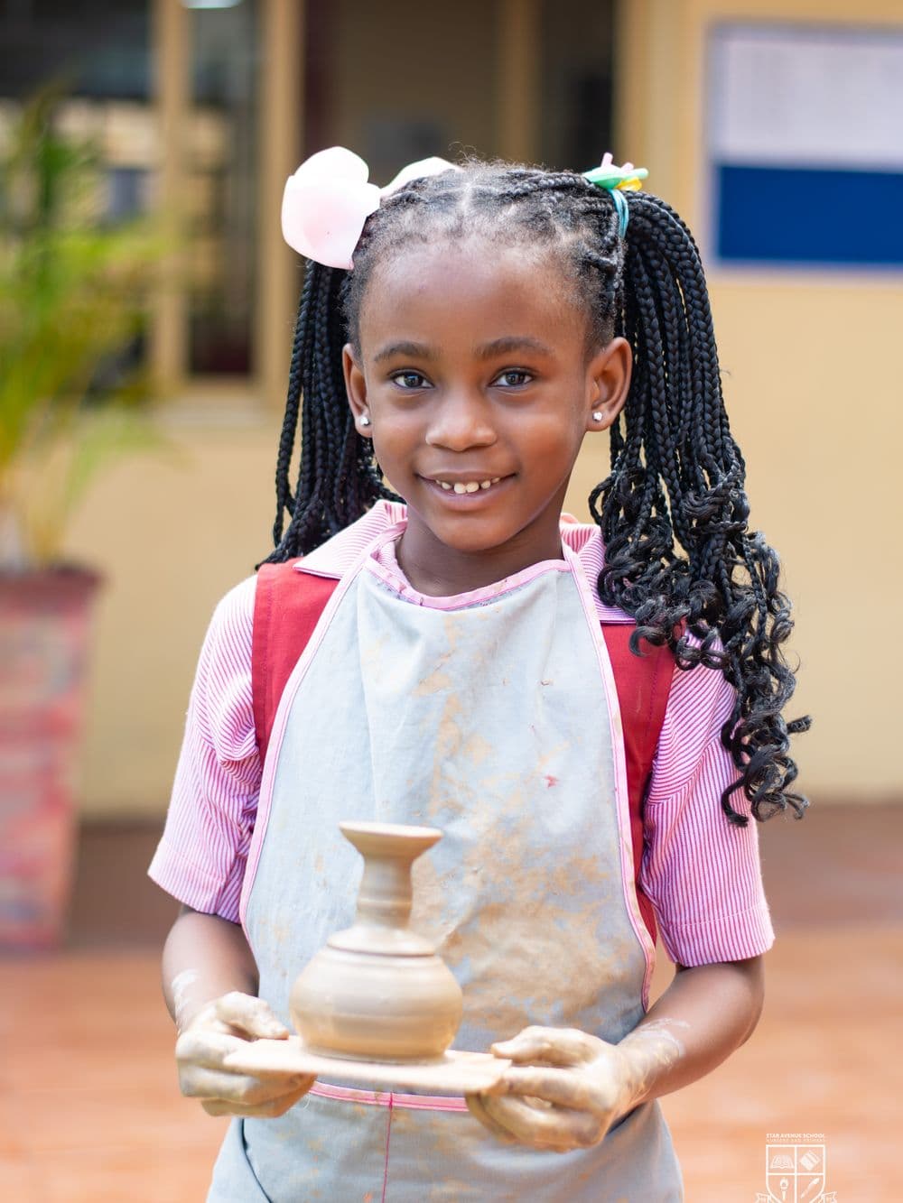 A pupil holding up the clay pot she has just finished