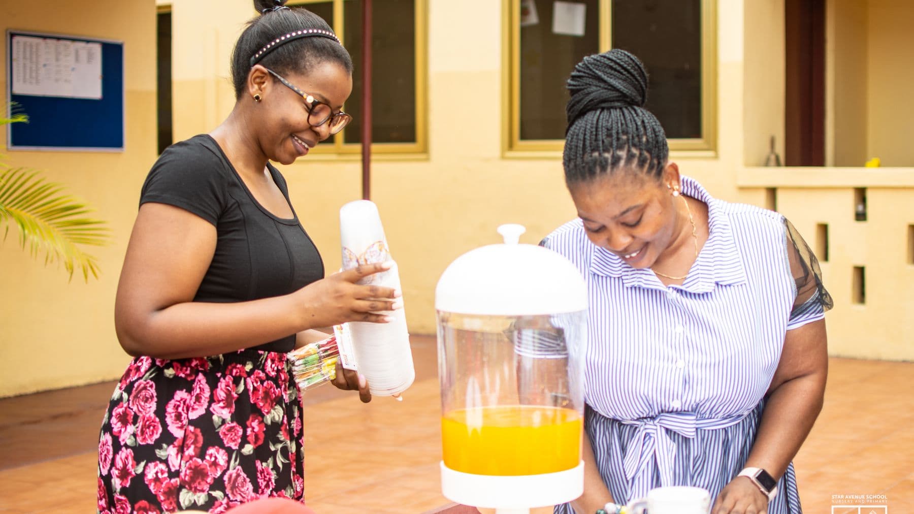 Two members of staff preparing refreshments before a school event