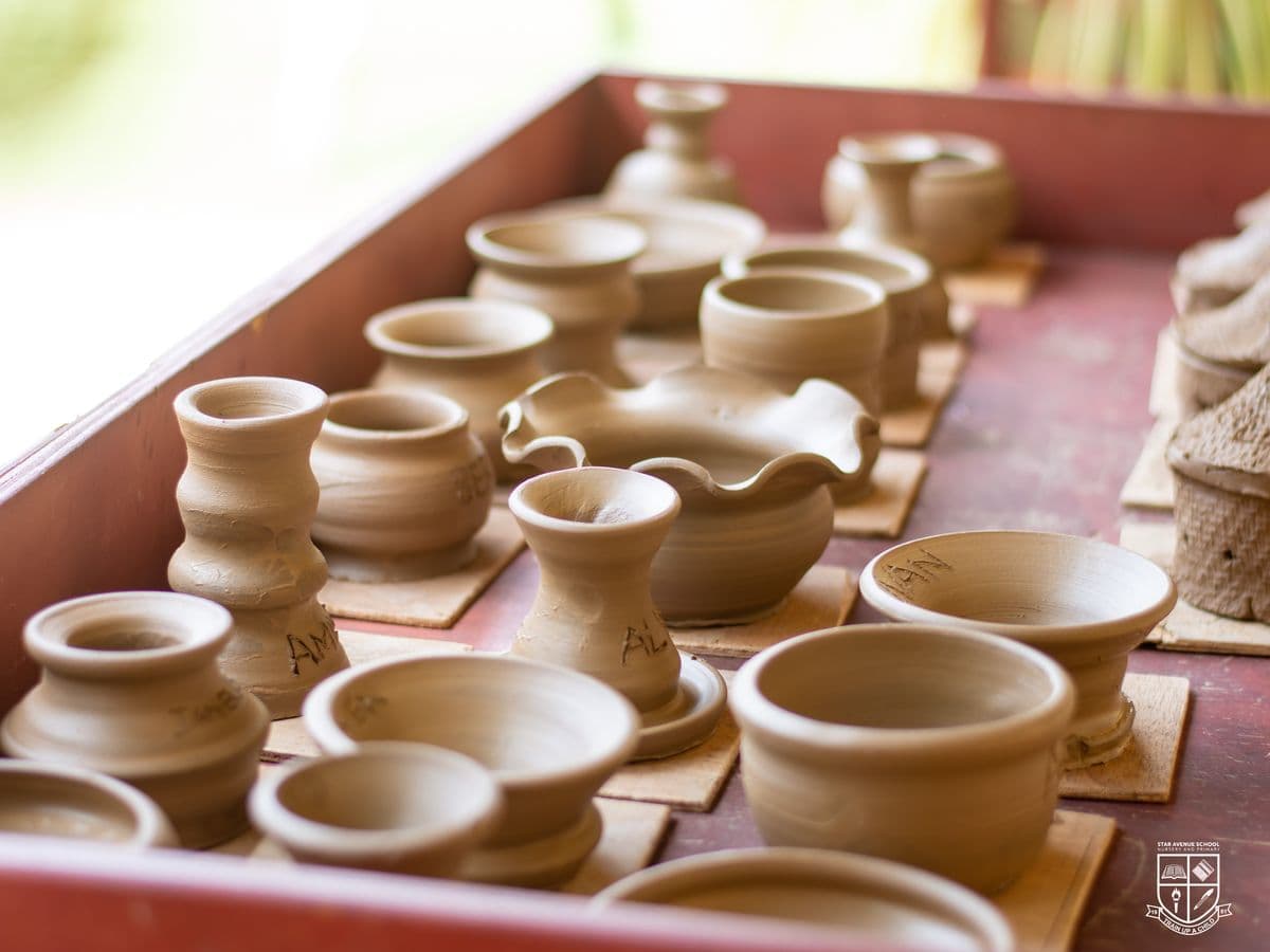 Rows of finished clay pots drying on a wooden tray