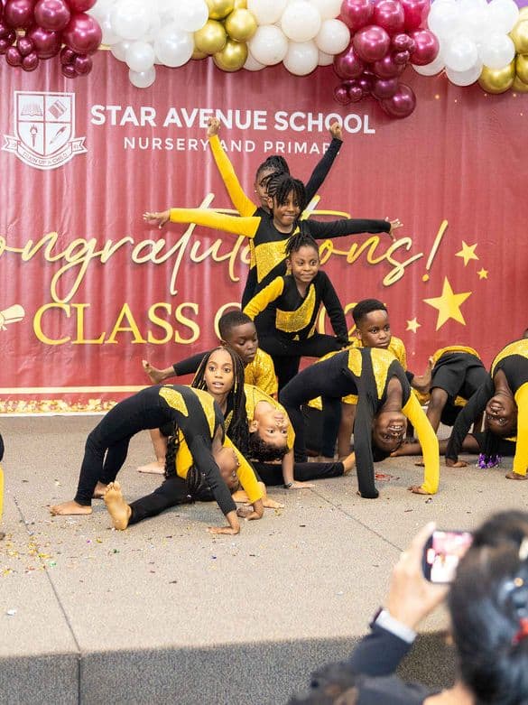 Pupils in yellow performing an acro dance routine on stage