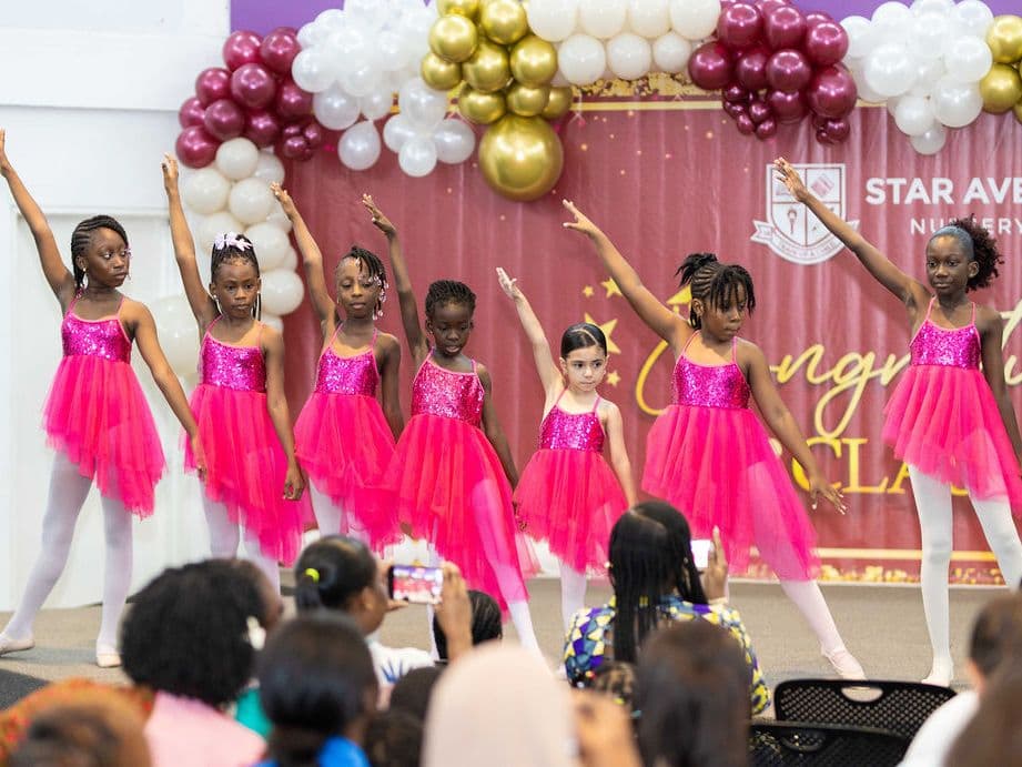 Young dancers in pink tutus lined up on stage