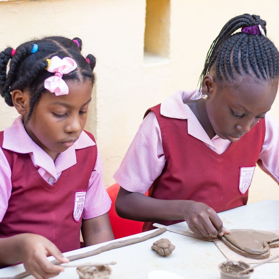 Two pupils shaping clay at the pottery table