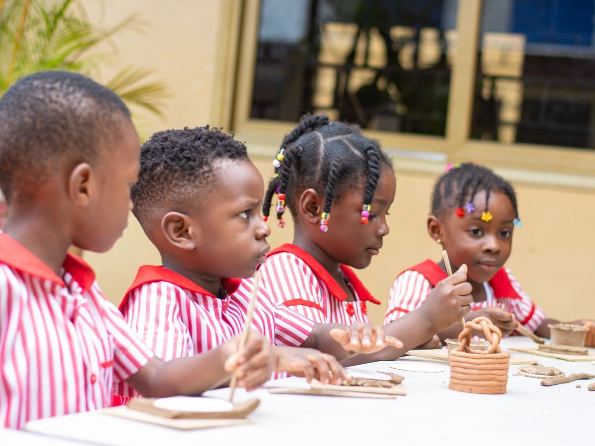 Four of the youngest pupils working side by side with clay at one table