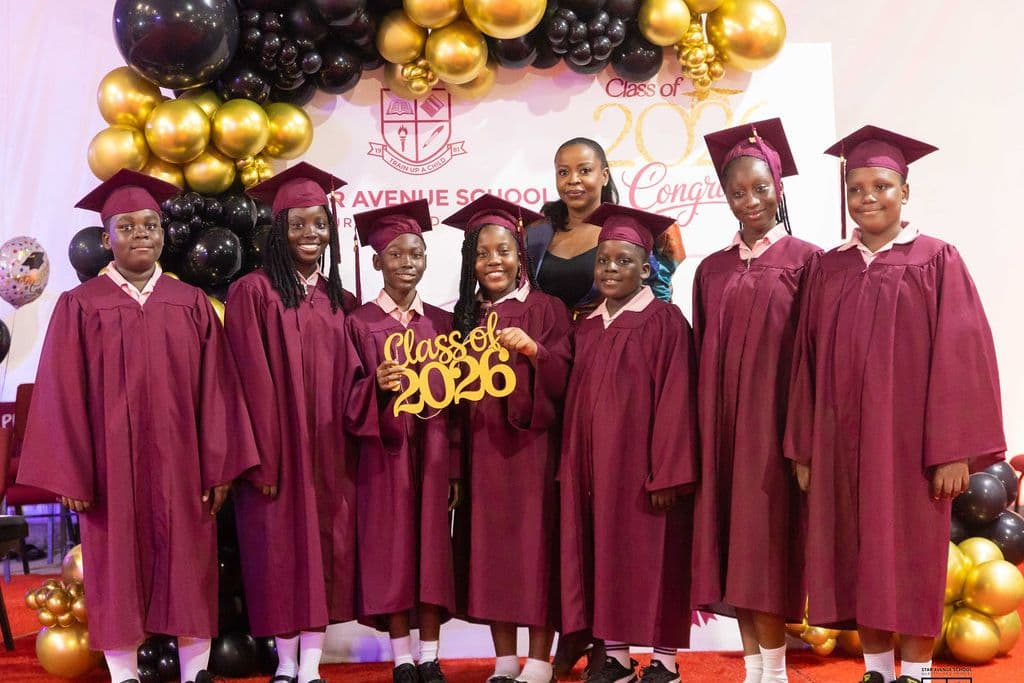 The graduating class in gowns and caps in front of the Class of 2026 banner