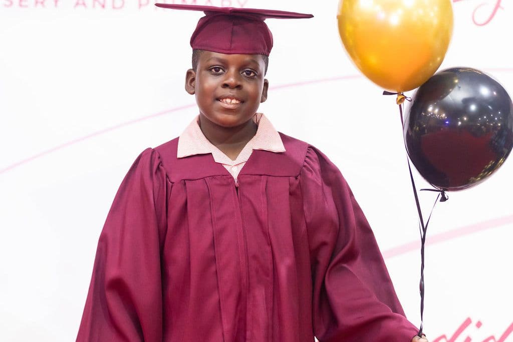 A graduate in cap and gown holding a balloon after the ceremony