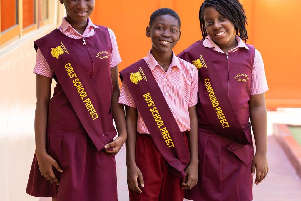 Three school prefects in uniform outside the classrooms