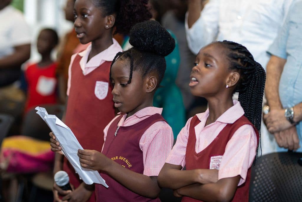 Two pupils reading aloud from a script at the microphone