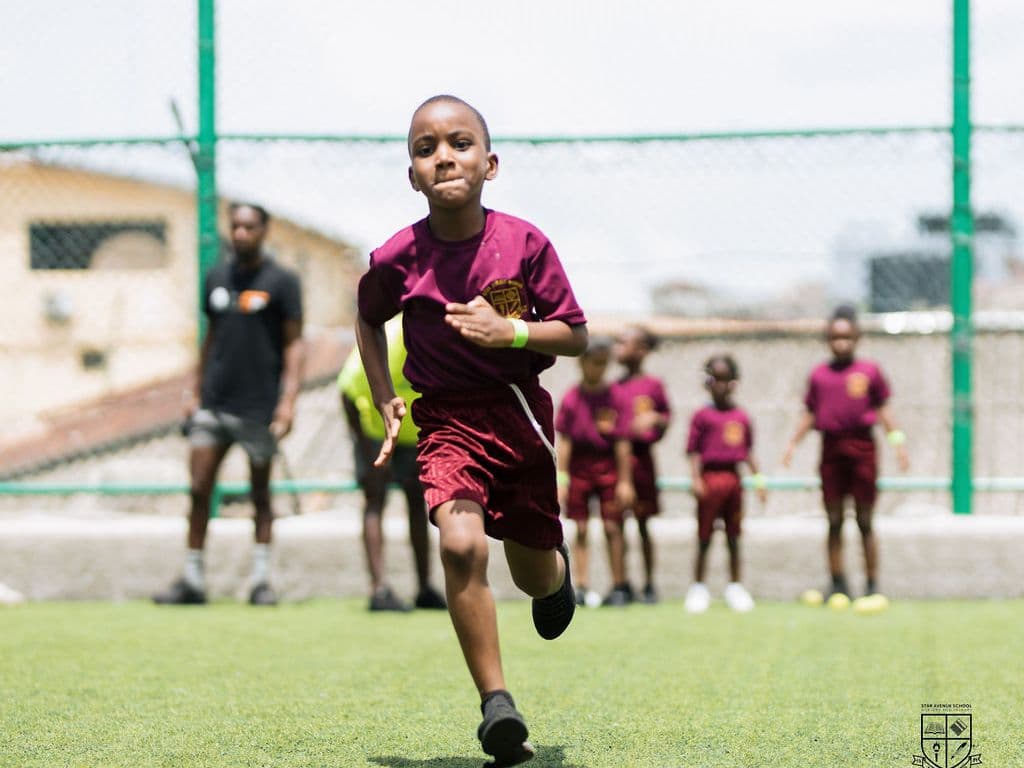 A pupil in Star Avenue sports kit running with the ball on the pitch