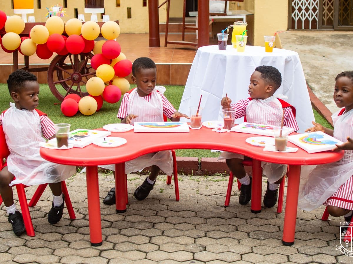 Nursery and Kindergarten children at their table in the school courtyard