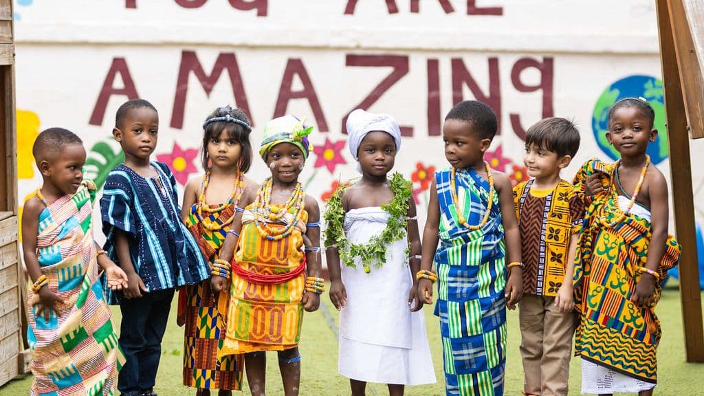 Pupils in traditional dress from across Africa in front of the school's painted wall